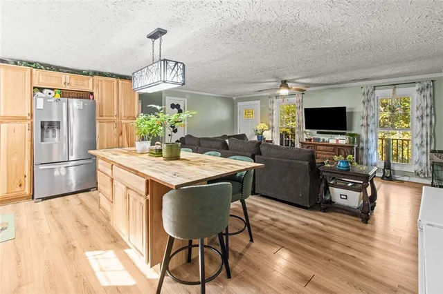 a kitchen with stainless steel appliances granite countertop a stove a refrigerator a kitchen island a dining table and chairs with wooden floor