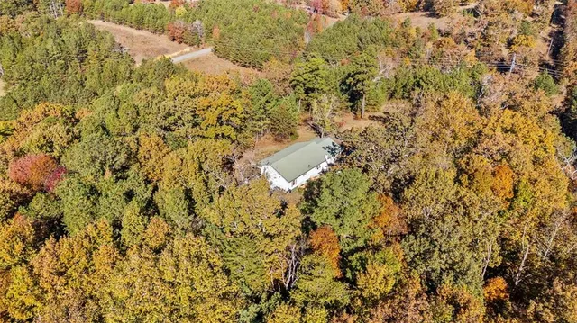an aerial view of residential house with outdoor space and trees all around