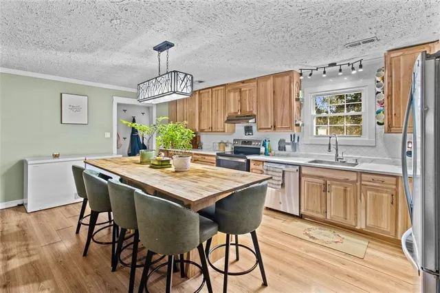 a kitchen with stainless steel appliances granite countertop a table chairs stove and refrigerator