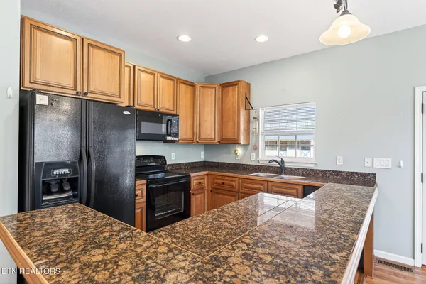 a kitchen with granite countertop a refrigerator and wooden cabinets