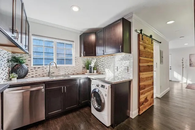 a utility room with stainless steel appliances granite countertop a sink and dishwasher a stove with wooden floor