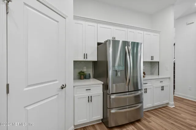a kitchen with stainless steel appliances kitchen island granite countertop a dining table chairs and a refrigerator
