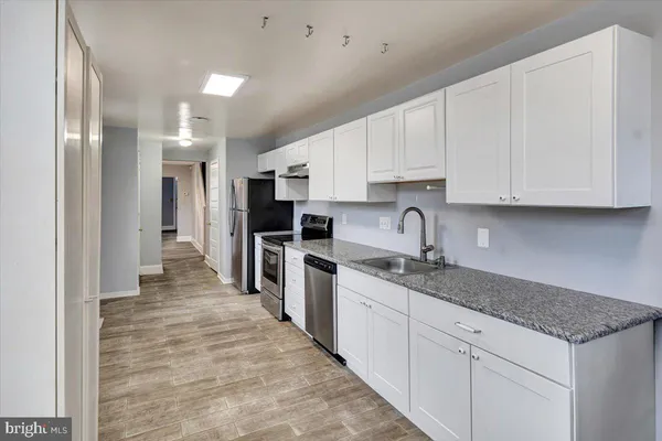 a kitchen with granite countertop a sink stainless steel appliances and white cabinets