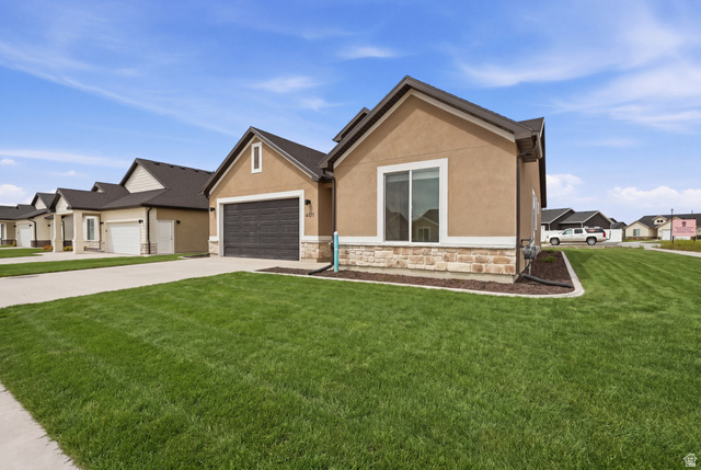401 West 3085 South, Unit 329 Nibley, UT 84321 - Photo 2 of 34 View of front facade featuring stone siding, stucco siding, a residential view, concrete driveway, and a front lawn