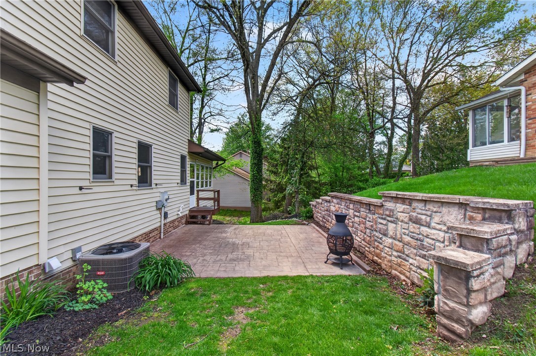 5346 Burlawn Street Northwest Canton, OH 44708 - Photo 33 of 40 Rear exterior featuring light-colored siding, a stamped concrete patio, and a stone retaining wall