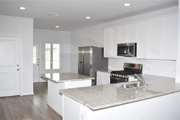 a kitchen with stainless steel appliances granite countertop a sink a stove a microwave a counter top space and cabinets