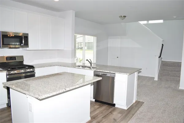 a kitchen with stainless steel appliances granite countertop a sink stove and microwave