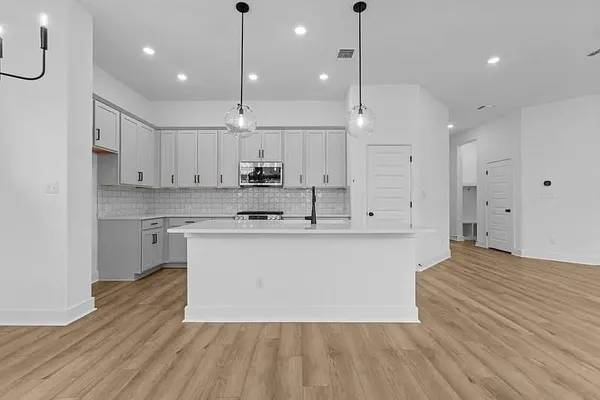 a large kitchen with cabinets wooden floor and stainless steel appliances