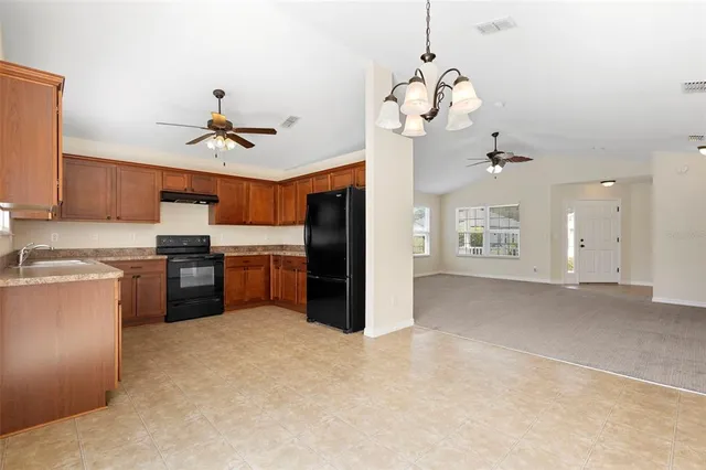a kitchen with stainless steel appliances granite countertop a sink a stove a refrigerator cabinets and a window