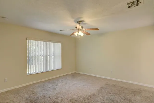 an empty room with windows and fan