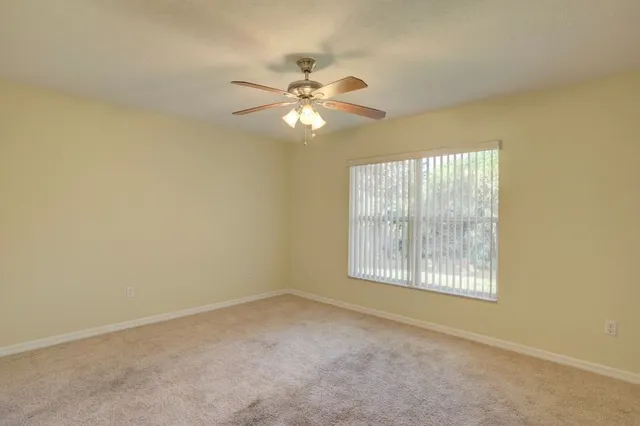 an empty room with windows and fan