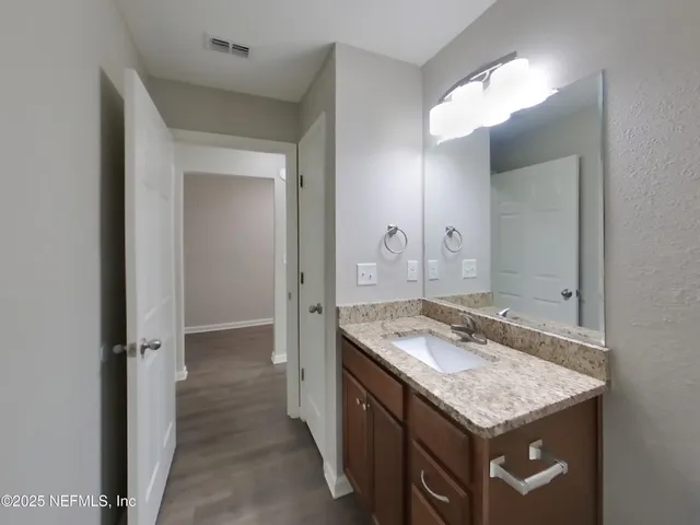 a bathroom with a granite countertop sink toilet and a mirror