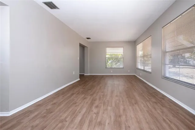 an empty room with wooden floor and windows