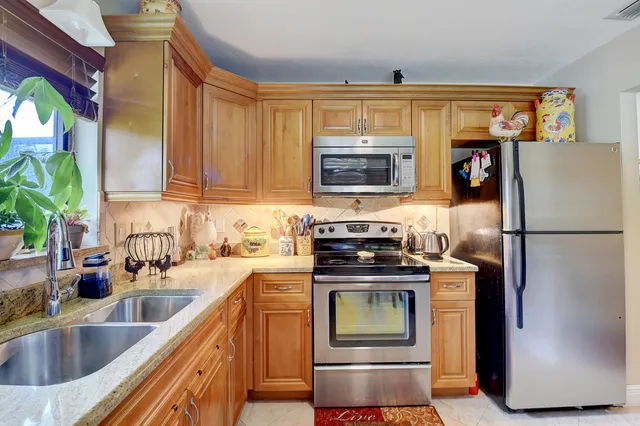 a kitchen with stainless steel appliances granite countertop a refrigerator a stove a sink and a microwave