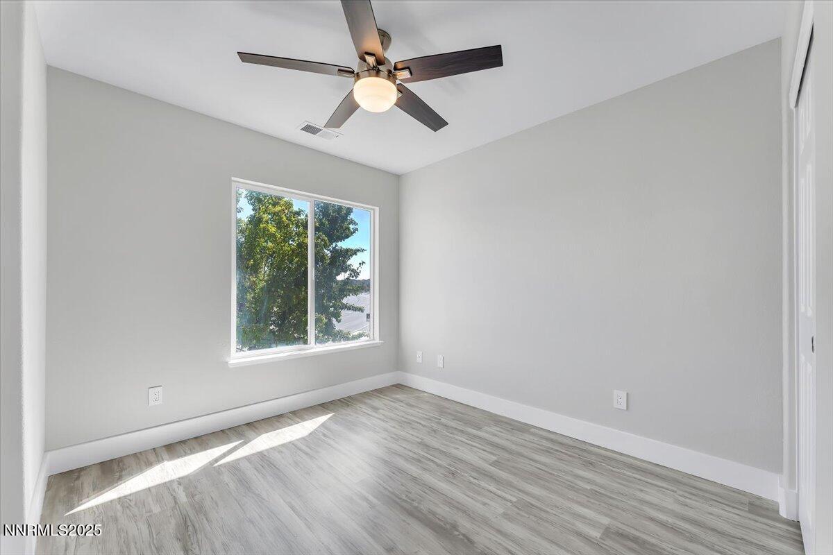 9252 Lone Wolf Circle Reno, NV 89506 - Photo 19 of 26 an empty room with wooden floor chandelier fan and windows
