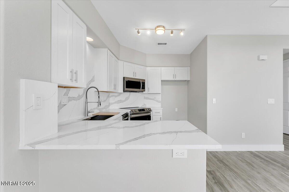 9252 Lone Wolf Circle Reno, NV 89506 - Photo 8 of 26 a kitchen with stainless steel appliances a sink a stove a microwave a refrigerator a white cabinets and wooden floor