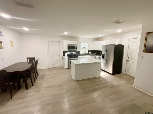 a large kitchen with a refrigerator a stove top oven a sink and dishwasher