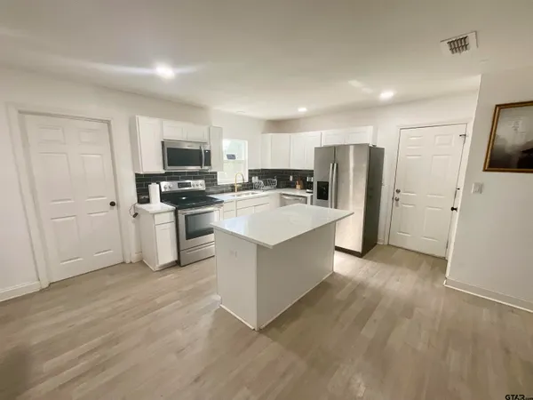 a living room with stainless steel appliances furniture and kitchen view