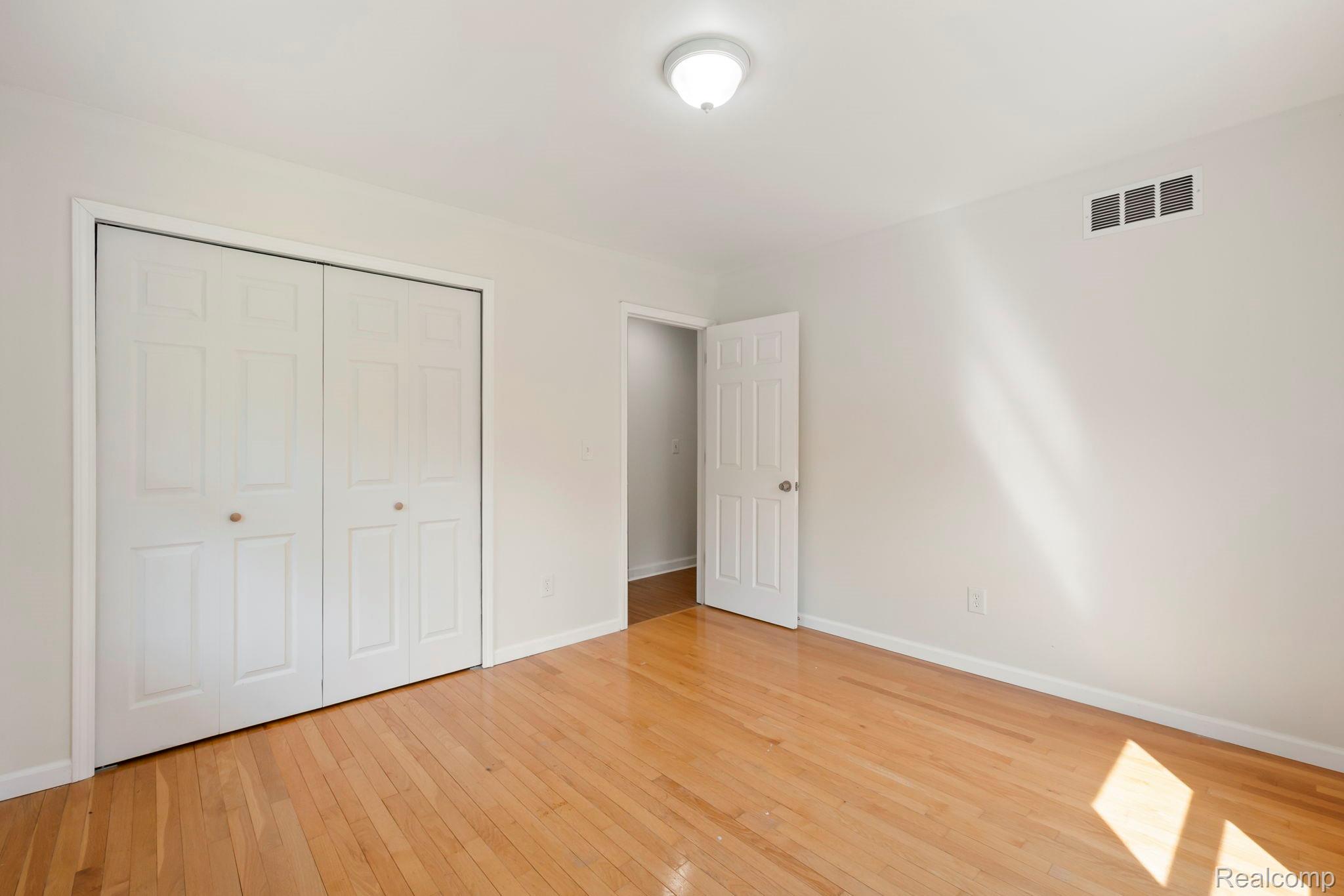 76565 McFadden Road Armada, MI 48005 - Photo 34 of 95 Warm wood-finish flooring with white baseboards, a flush-mount ceiling light, and white paneled bi-fold closet doors