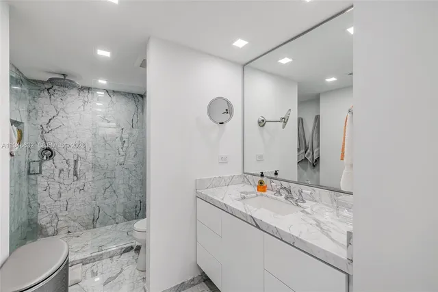 a bathroom with a granite countertop sink a toilet and shower