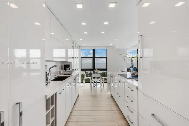 a large white kitchen with lots of counter space a sink and appliances