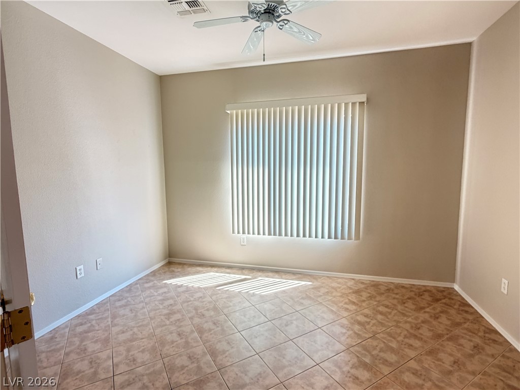 2523 Romanza Road Henderson, NV 89052 - Photo 21 of 24 A well-lit bedroom features durable tile flooring and a ceiling fan for comfort.
