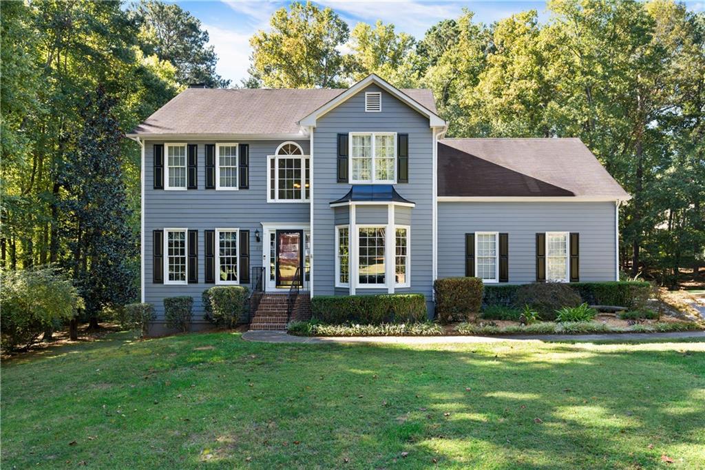 a front view of a house with a yard and trees