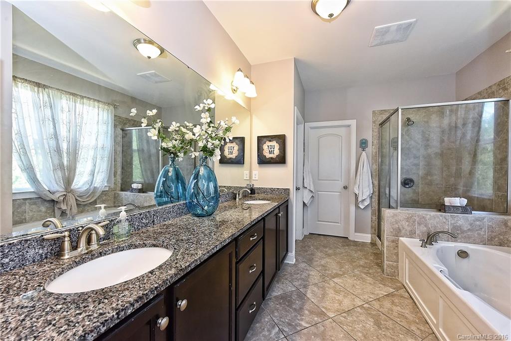 3004 Fallondale Road, Unit 906 Waxhaw, NC 28173 - Photo 14 of 24 a bathroom with a granite countertop double vanity sink a large mirror and a bathtub