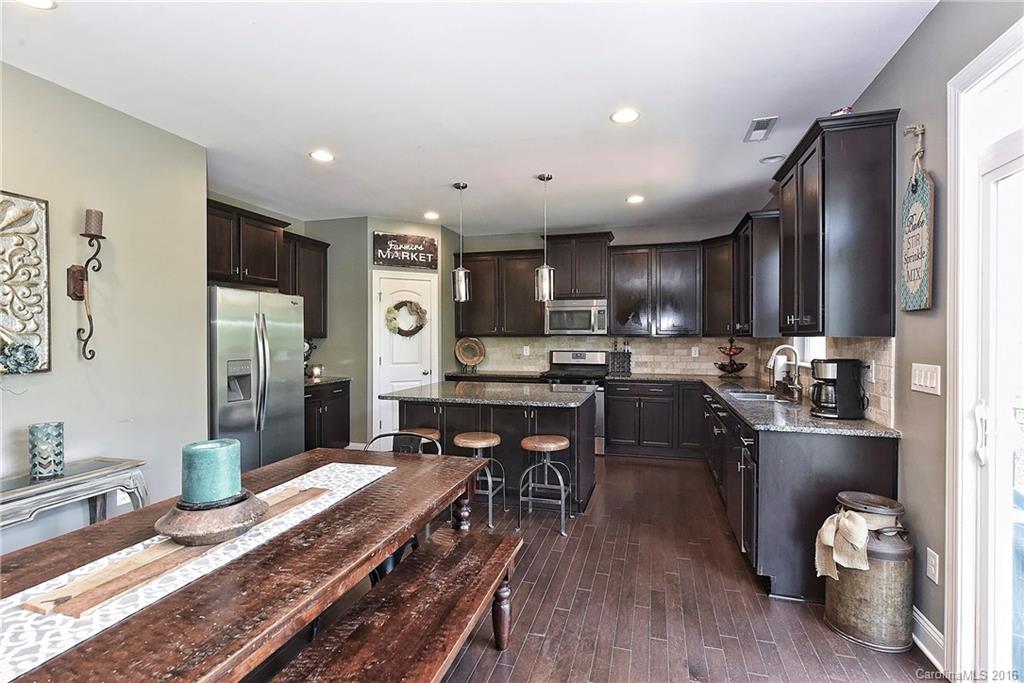3004 Fallondale Road, Unit 906 Waxhaw, NC 28173 - Photo 8 of 24 a kitchen with stainless steel appliances granite countertop a refrigerator a sink dishwasher a stove and a dining table with wooden floor
