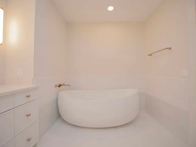 a bathroom with a double vanity sink and mirror with bathtub