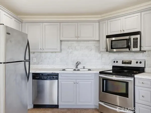 a kitchen with white cabinets and stainless steel appliances