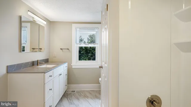 a bathroom with a granite countertop sink mirror and a bathtub