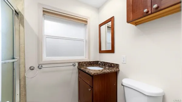 a bathroom with a granite countertop sink toilet and a mirror