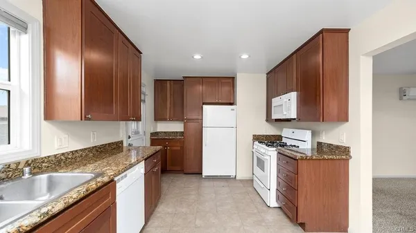 a kitchen with granite countertop stainless steel appliances a refrigerator stove top oven and sink