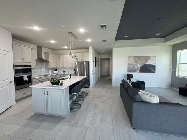 a large white kitchen with cabinets a sink a window and stainless steel appliances