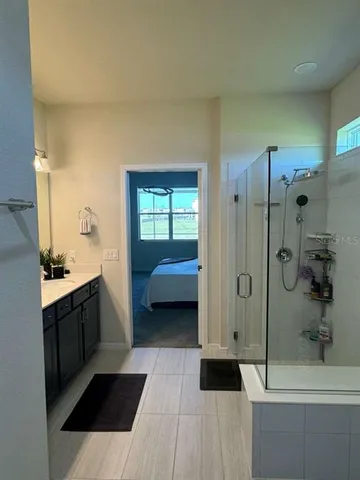 a en suite bathroom with a tub shower vanity and a sink