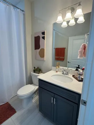 a bathroom with a sink a toilet a mirror and shower curtain
