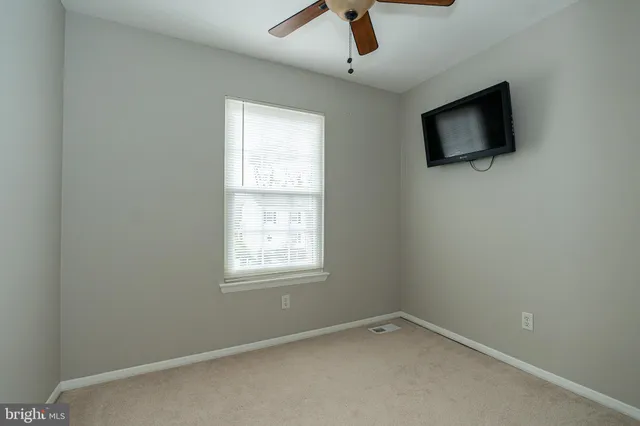 an empty room with a window and a fan