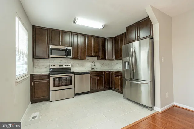 a kitchen with kitchen island wooden cabinets stainless steel appliances and a window