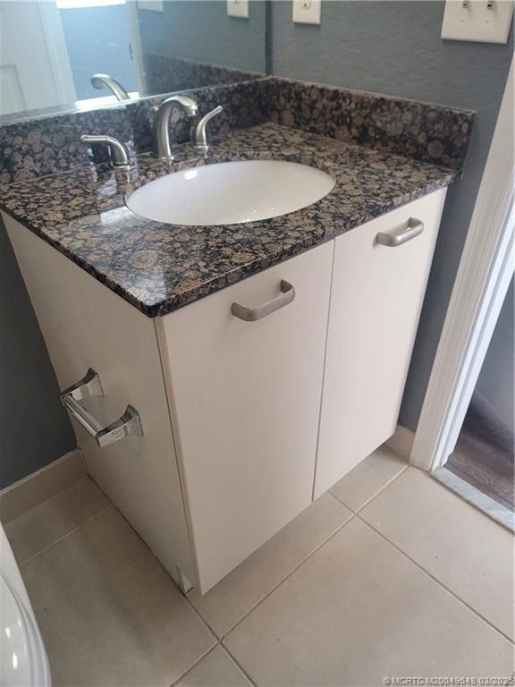59 Southeast Palermo, Unit 204 Stuart, FL 34994 - Photo 12 of 23 a bathroom with a granite countertop sink and a mirror