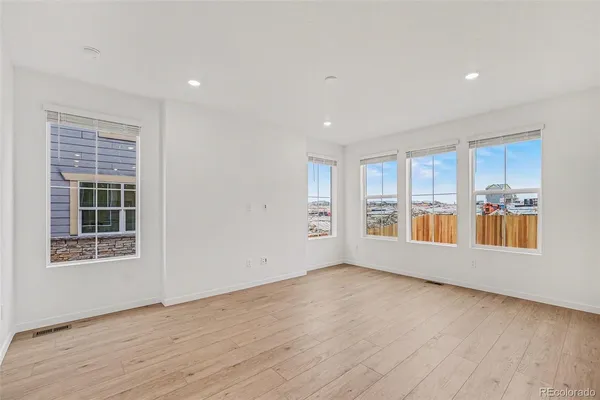 a view of an empty room with a window and wooden floor