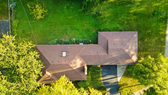an aerial view of a house with a yard and a large tree