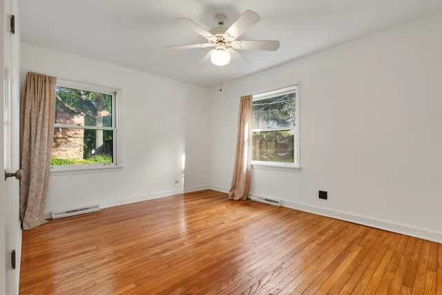 a view of an empty room with window and wooden floor