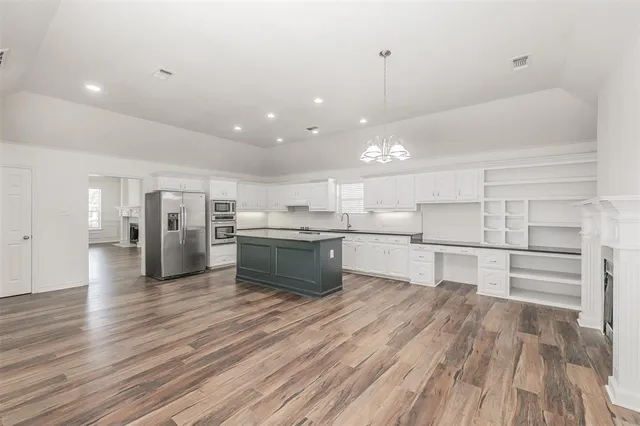 a kitchen with stainless steel appliances refrigerator wooden floor and window