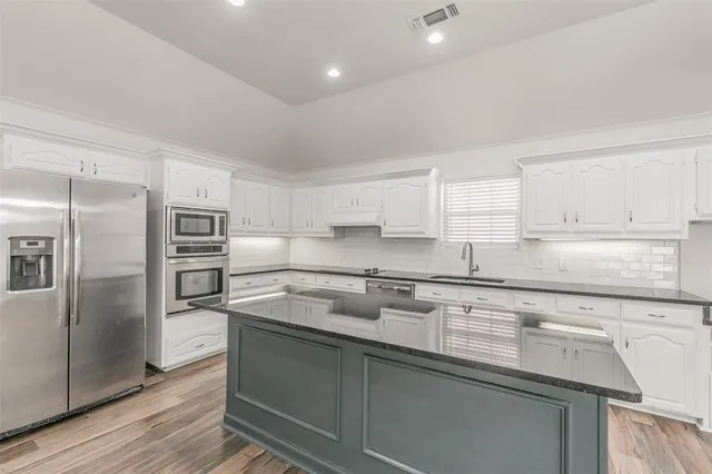 a kitchen with a refrigerator sink and cabinets
