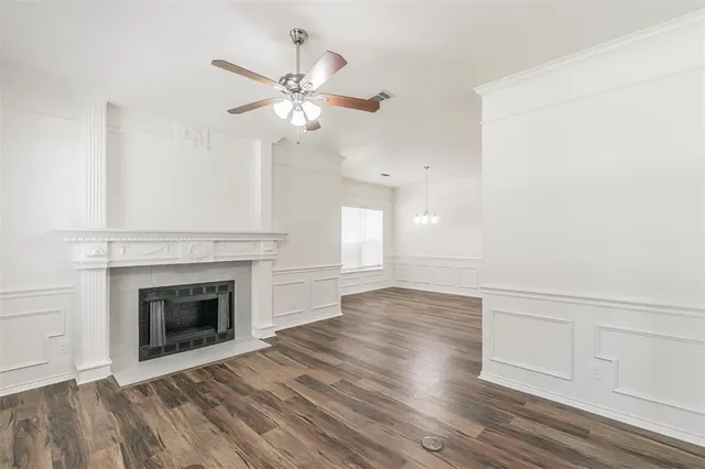 a view of an empty room with wooden floor and fireplace