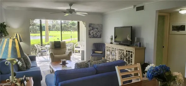 a living room with furniture a flat screen tv and a floor to ceiling window