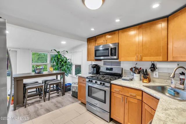 a kitchen with stainless steel appliances a stove a sink a microwave a refrigerator and cabinets