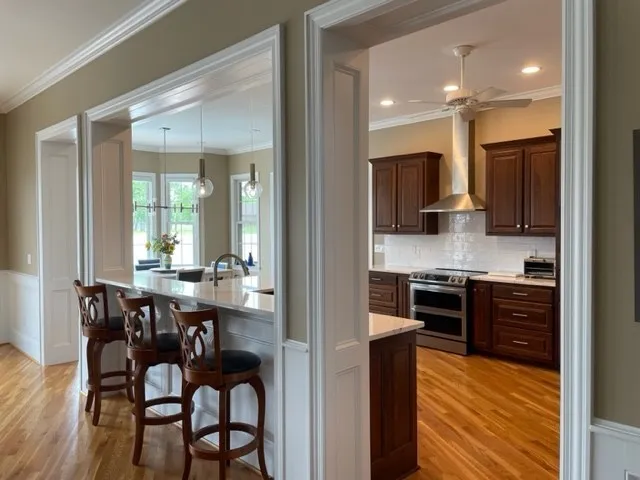 a kitchen with stainless steel appliances granite countertop a stove top oven a sink a dining table and chairs with wooden floor