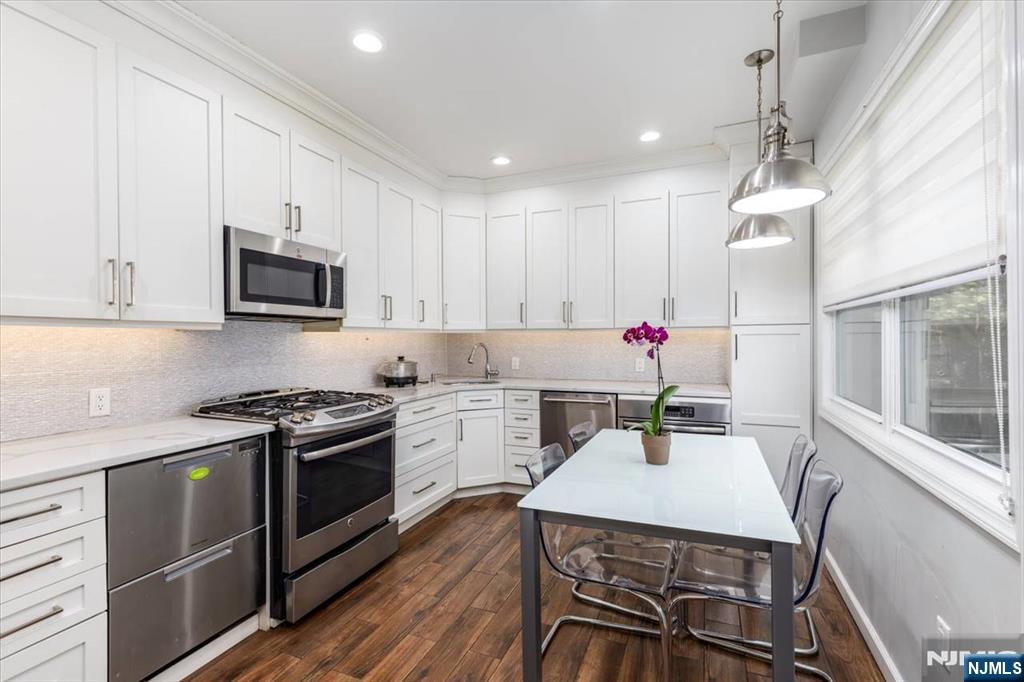 116 Westervelt Place Passaic, NJ 07055 - Photo 11 of 25 a kitchen with a stove a sink cabinetry a dining table and chairs